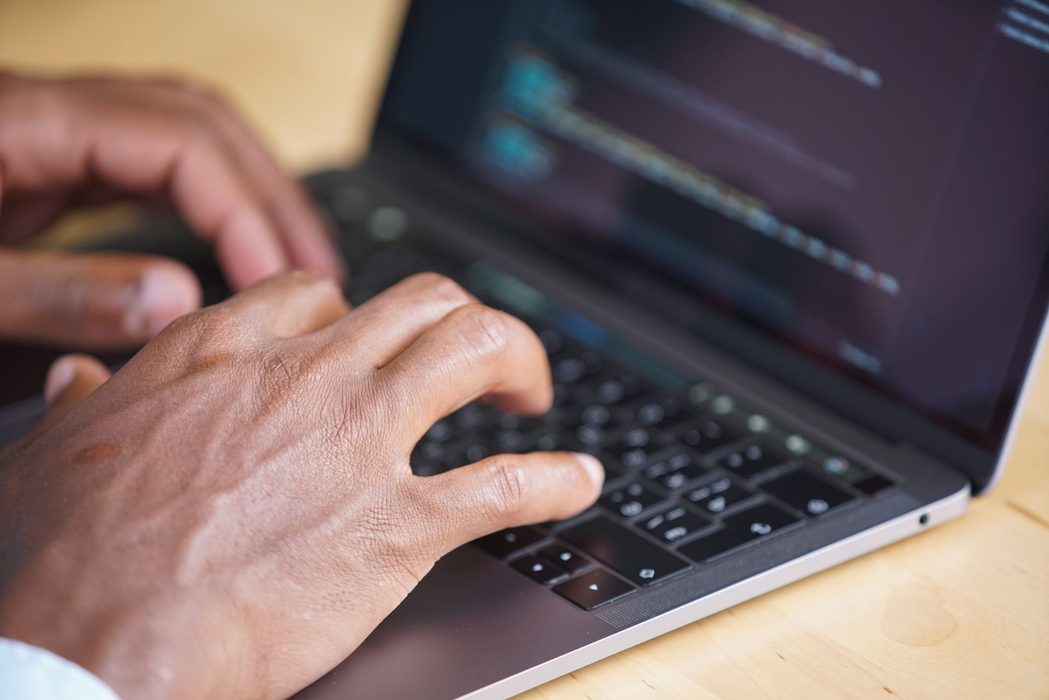 A person typing commands into a terminal window on a laptop at a desk